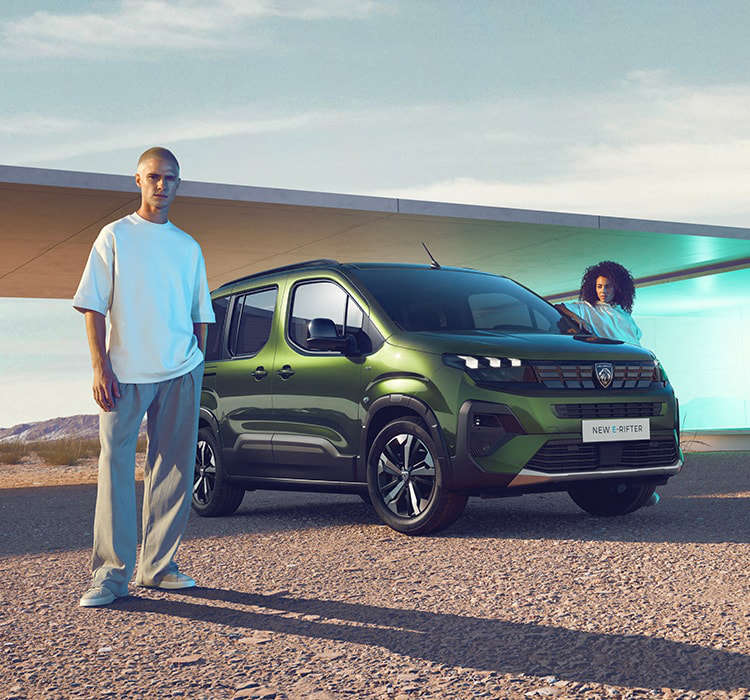 Чоловік стоїть перед Peugeot e-Rifter, жінка біля водійських дверей